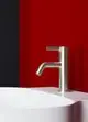 Ideal Standard Wasserhahn in Silber vor rot-schwarzer Wand, montiert auf einer ovalen, weißen Waschschüssel.